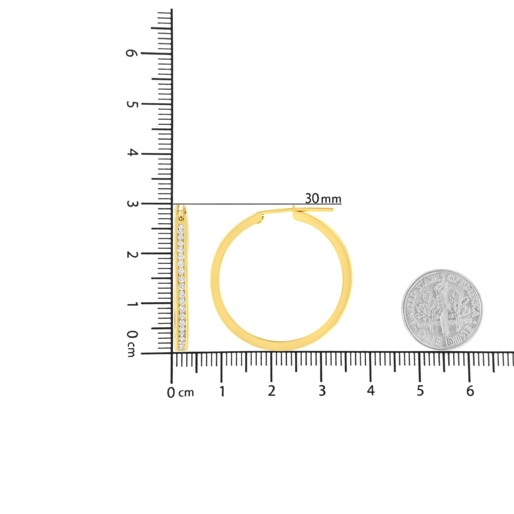 Front and side views of yellow metal hoop earrings with channel-set round white gemstones, shown on a ruler for size reference.