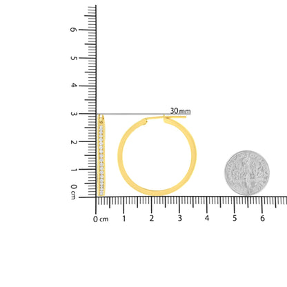 Front and side views of yellow metal hoop earrings with channel-set round white gemstones, shown on a ruler for size reference.
