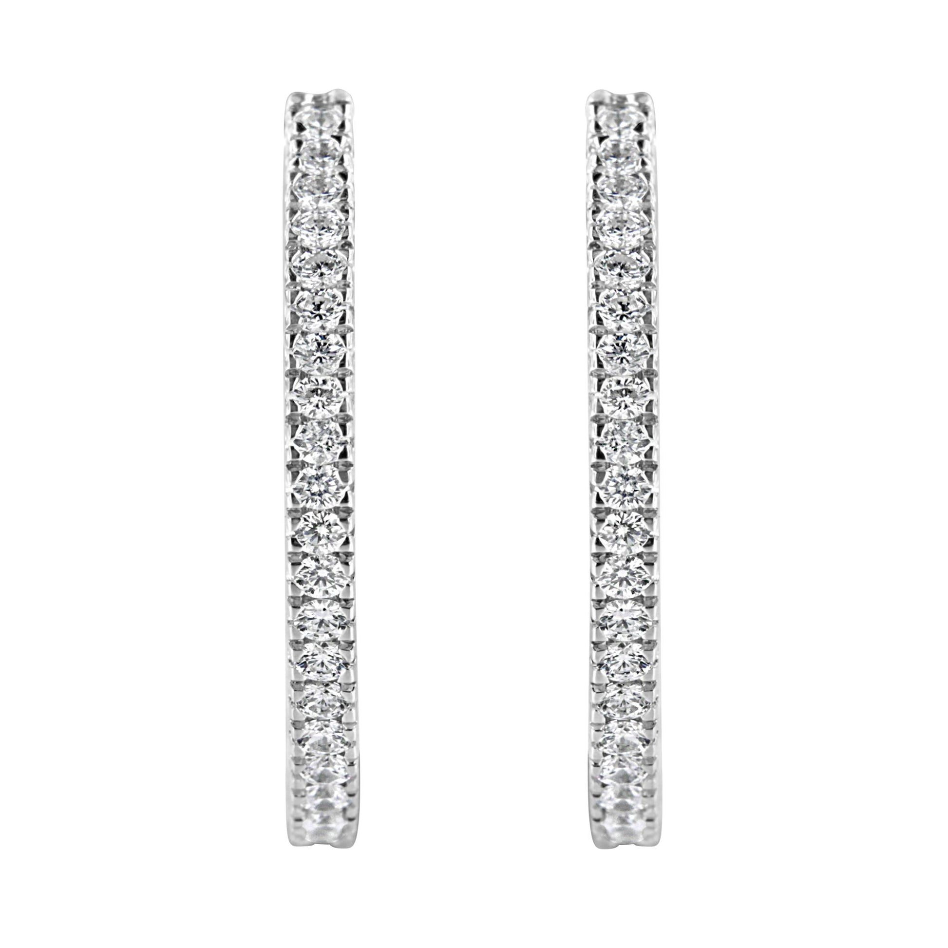 Front-facing close-up of a pair of white metal hoop earrings with round white gemstones in a pave setting.