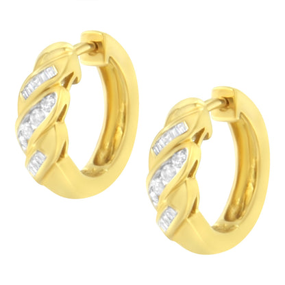 Pair of yellow metal hoop earrings with alternating rows of round and baguette white gemstones in a channel setting, shown from a front angle.