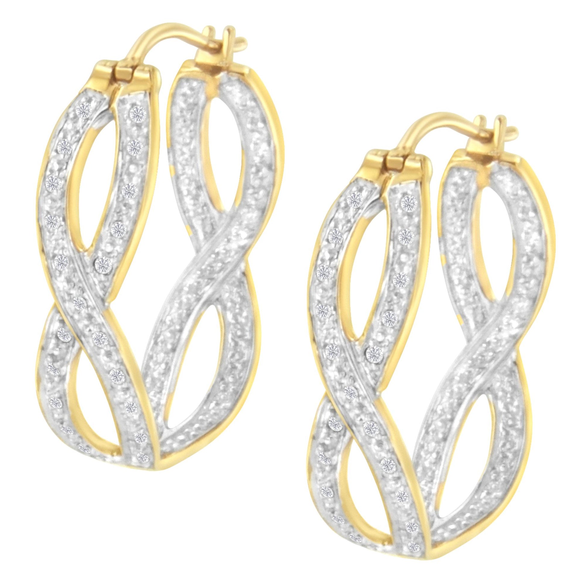 Front angled view of a pair of yellow metal earrings with intertwined oval shapes, decorated with white round prong-set gemstones.