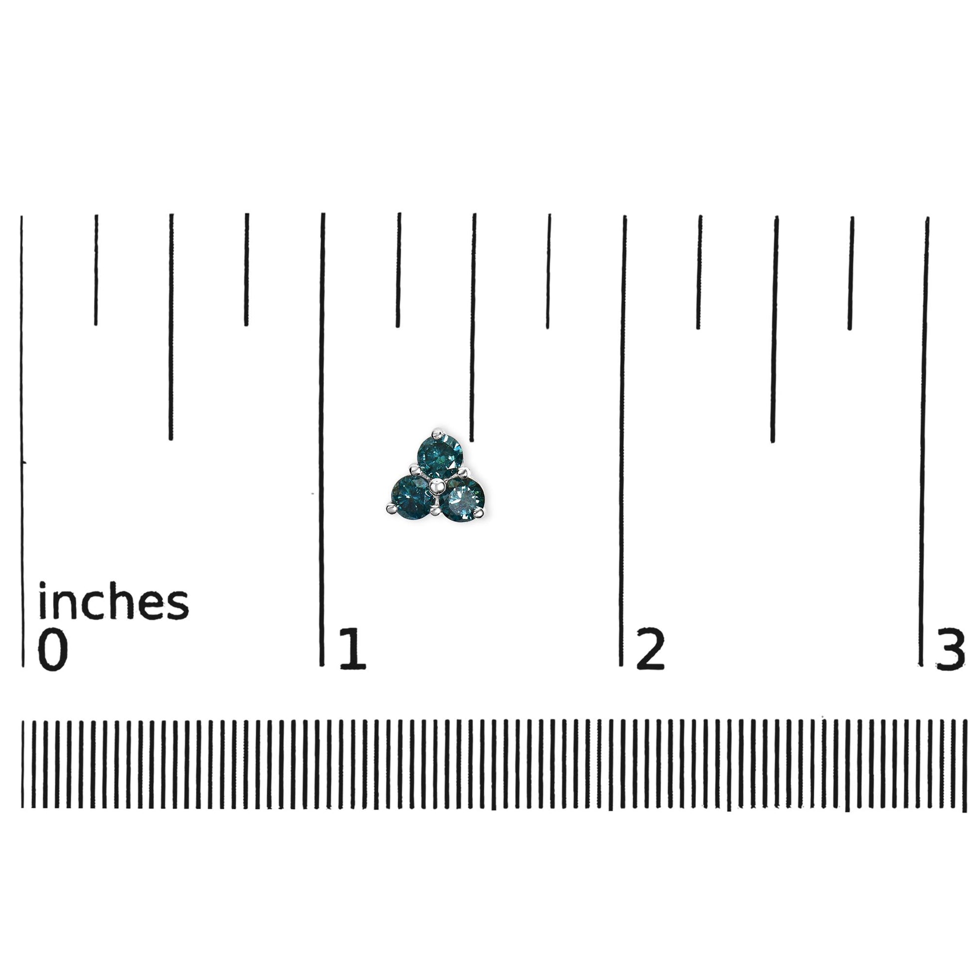 Close-up of a white metal earring with three round blue gemstones in prong settings, shown on a ruler for size reference.