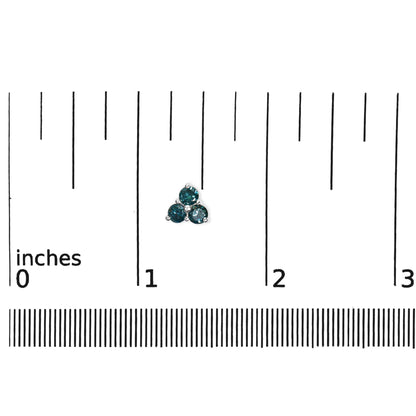 Close-up of a white metal earring with three round blue gemstones in prong settings, shown on a ruler for size reference.