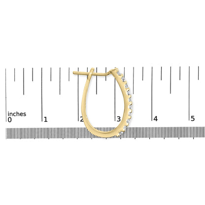 Single yellow metal earring with white round and baguette gemstones in channel setting, shown on a ruler for size reference, side view.