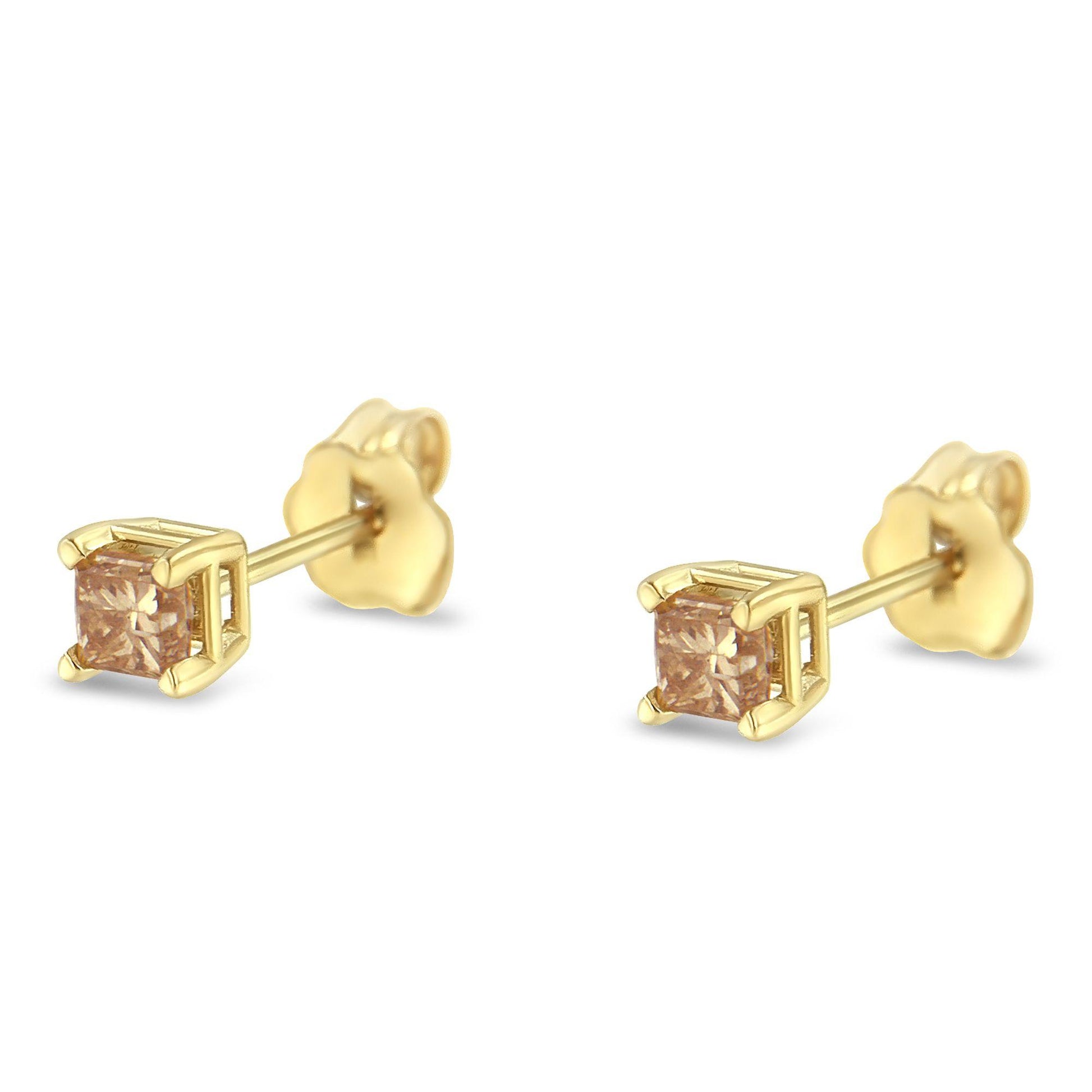 Pair of yellow metal stud earrings with square-shaped red gemstones in four-prong settings, shown from a side angle.