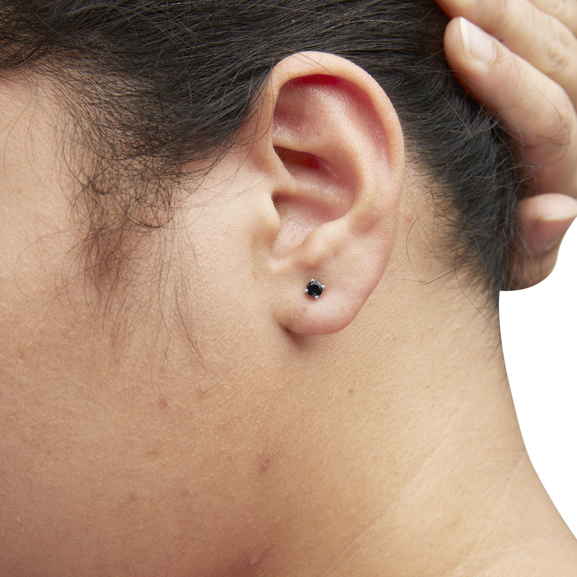 Close-up side view of a model wearing a single white metal earring with a round black gemstone in a prong setting.
