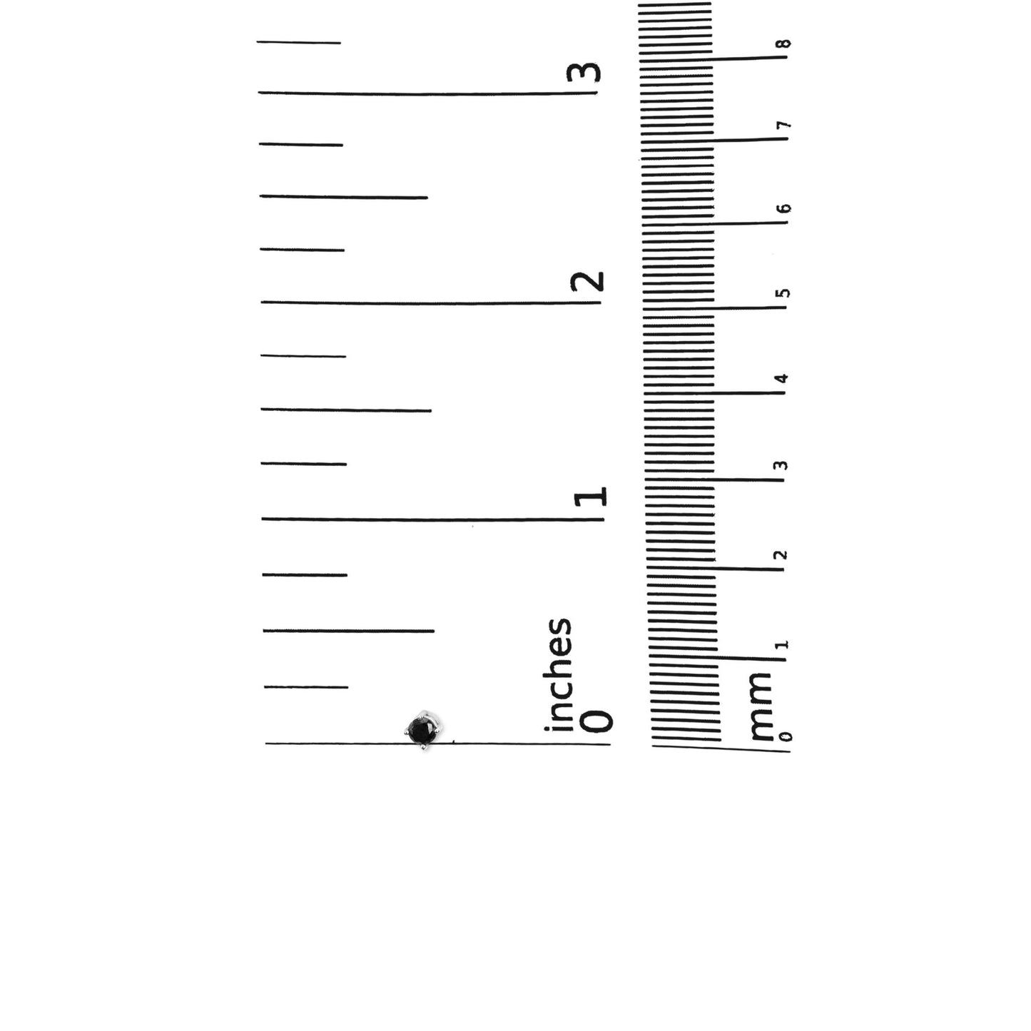 Single white metal stud earring with a round black gemstone in a four-prong setting, shown on a ruler for size reference, top-down angle.