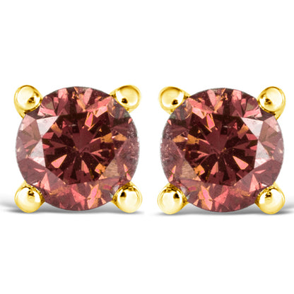 Close-up front view of a pair of yellow metal stud earrings with round pink gemstones in four-prong settings.