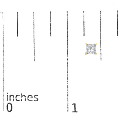 Close-up front view of a yellow metal princess-shaped stud earring with a brownish gemstone in a 4-prong setting, placed on a ruler for size reference.