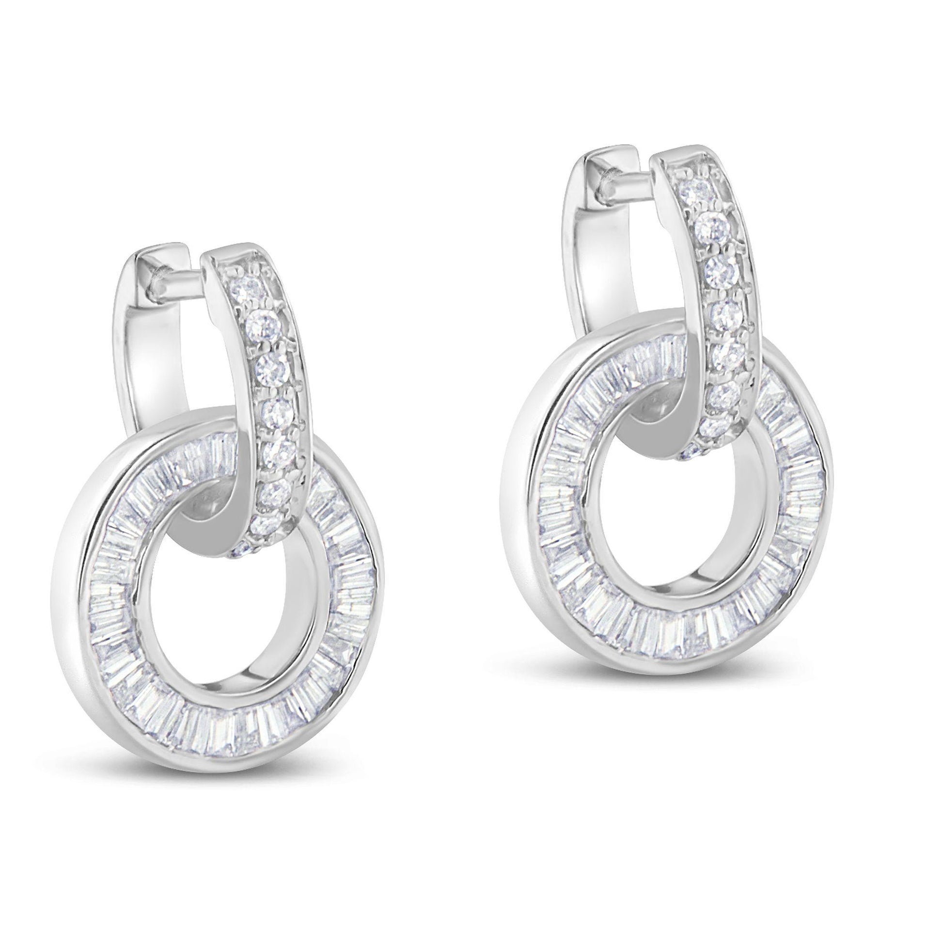 Pair of white metal earrings shown at a slight angle, each featuring a hoop with channel-set baguette white gemstones and a curved top section adorned with prong-set round white gemstones.