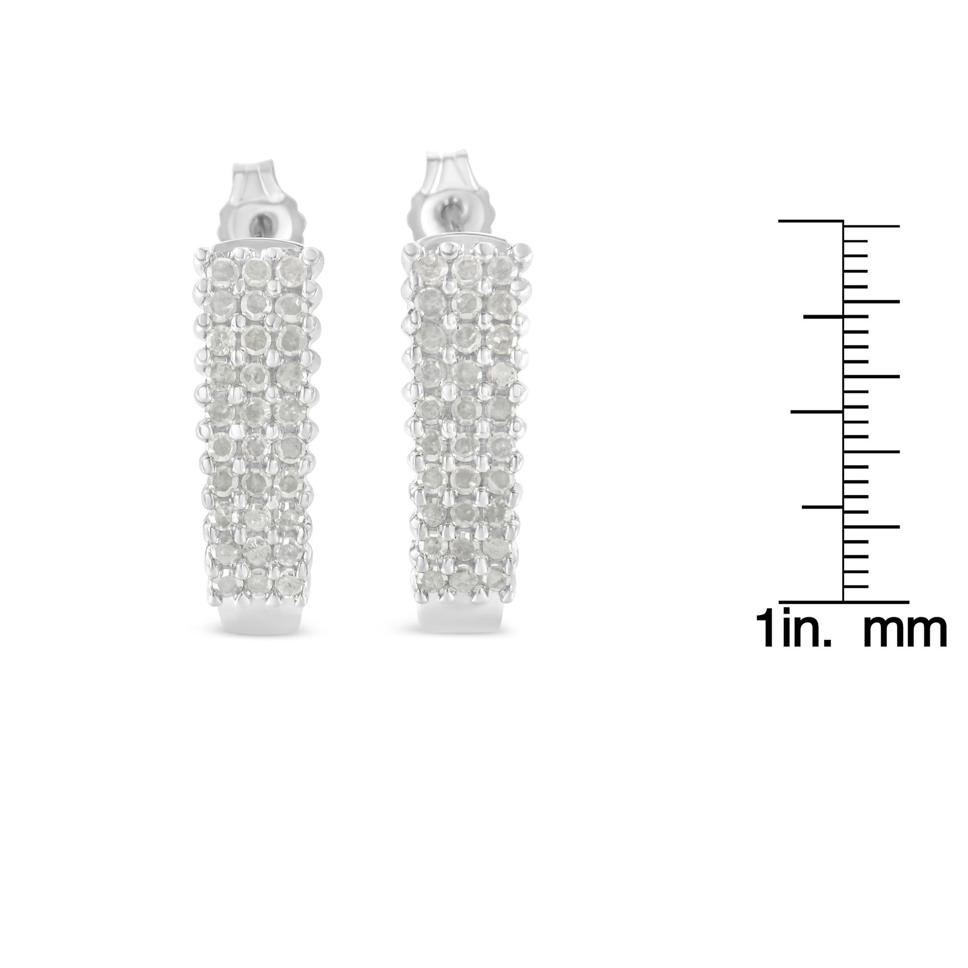 Pair of white metal earrings with multiple rows of round white gemstones in prong settings, front view, shown with a ruler for size reference.