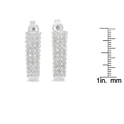Pair of white metal earrings with multiple rows of round white gemstones in prong settings, front view, shown with a ruler for size reference.