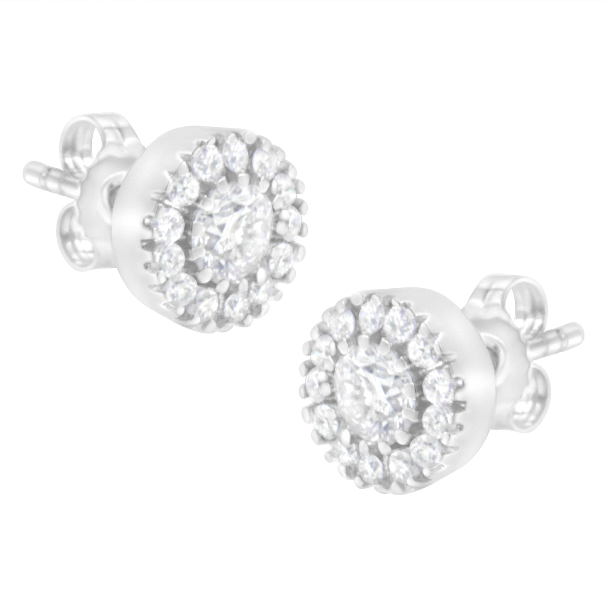Close-up side angle of a pair of white metal stud earrings featuring a central round prong-set white gemstone surrounded by a halo of smaller round pave-set white gemstones.