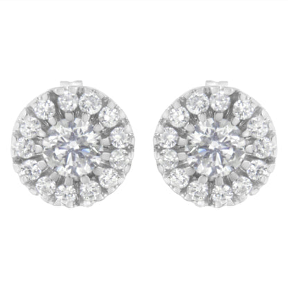 Front view of white metal round stud earrings featuring a central round white gemstone in prong setting surrounded by smaller round white gemstones in pave setting.