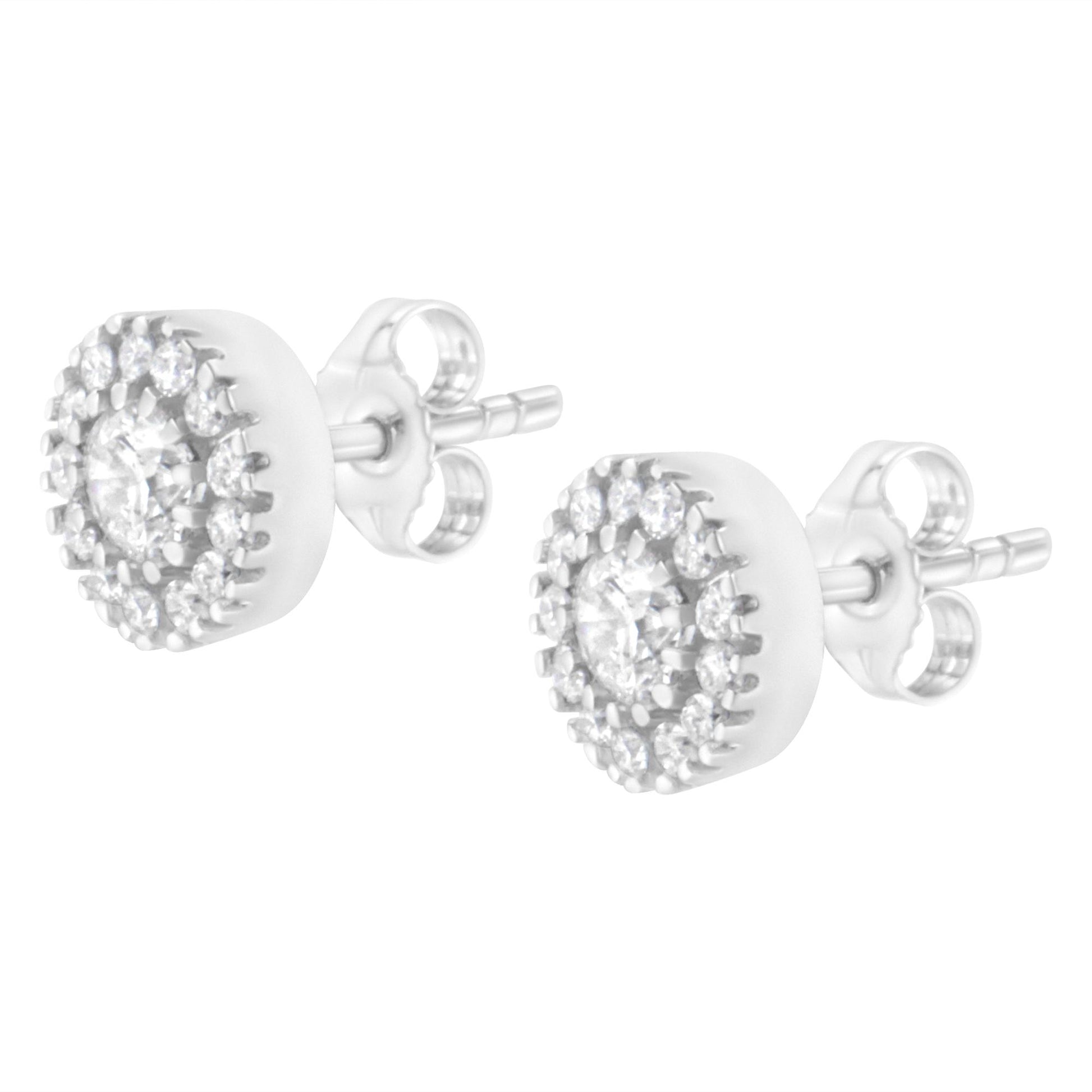 Pair of white metal stud earrings with round white gemstones, featuring a central prong setting surrounded by a pave setting, shown in a side angled view.