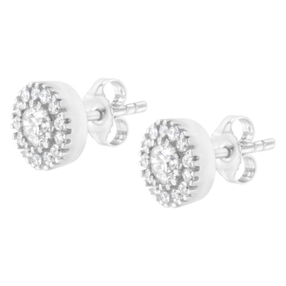 Pair of white metal stud earrings with round white gemstones, featuring a central prong setting surrounded by a pave setting, shown in a side angled view.