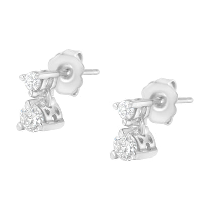 Pair of white metal stud earrings with round white gemstones in prong settings, shown at an angled close-up view.