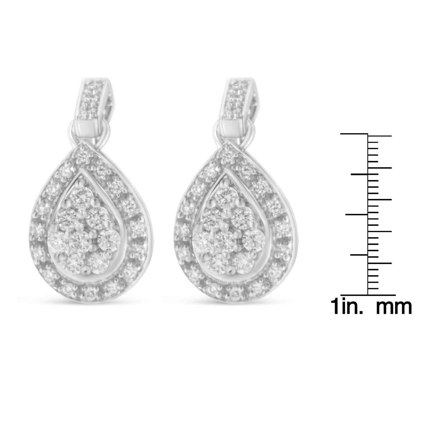 Front view of white metal teardrop-shaped earrings with prong-set round white gemstones, shown next to a ruler for size reference.