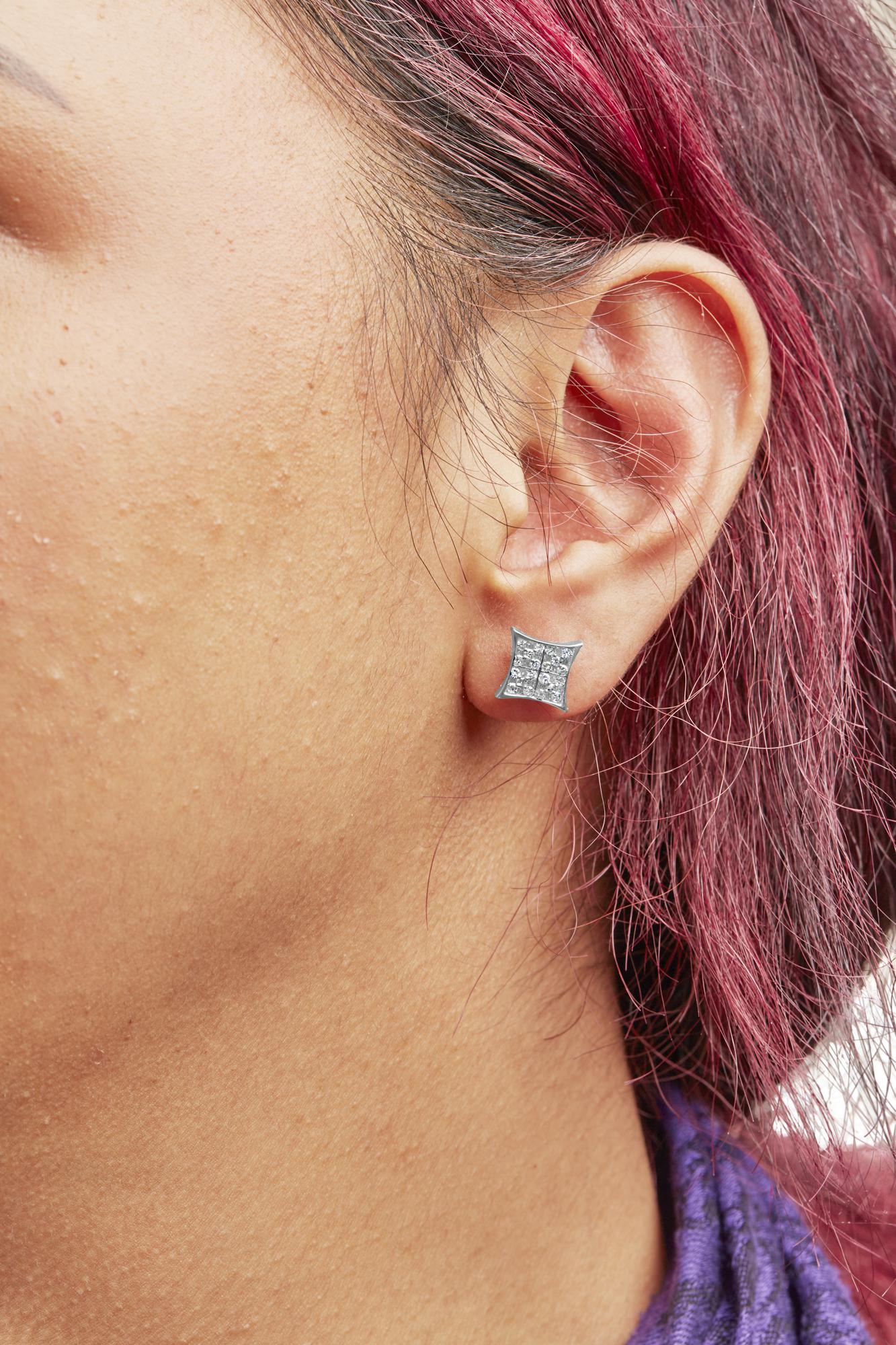 Close-up side view of a white metal square-shaped earring with prong-set white round gemstones worn on a model.
