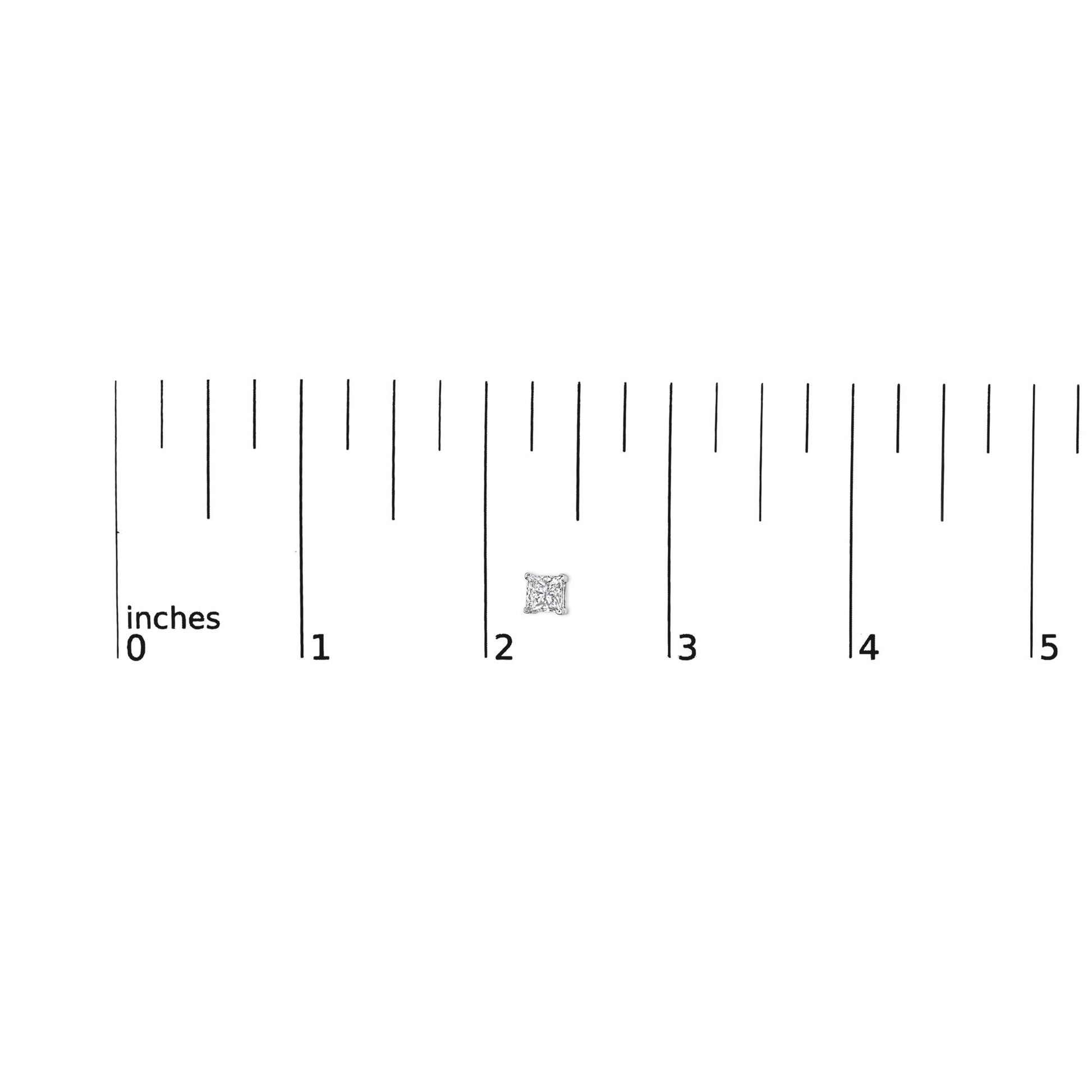 Close-up of a single white metal princess-shaped stud earring with a white gemstone in a 4-prong setting, positioned on a ruler for size reference.