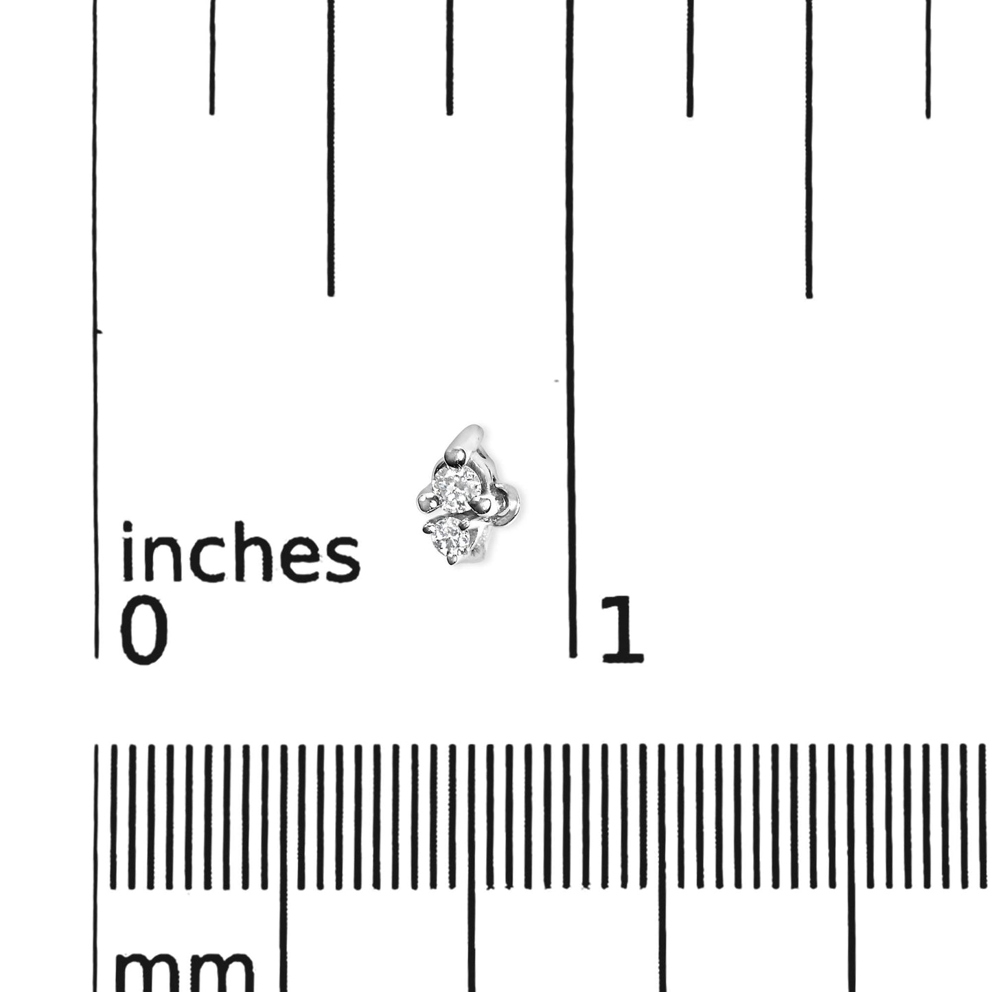 Close-up angled view of a white metal earring with two small round white gemstones in three-prong settings, placed on a ruler for size reference.