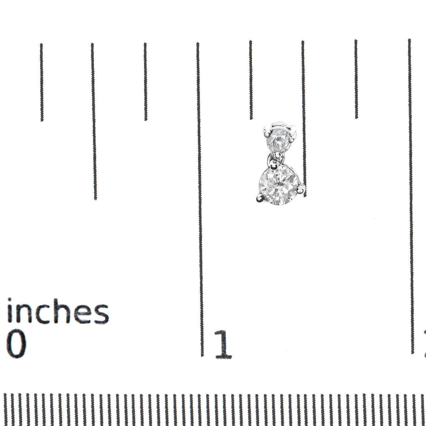 Close-up front view of white metal earrings with two round white gemstones in prong settings, shown on a ruler for size reference.
