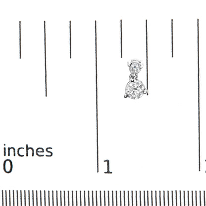 Close-up front view of white metal earrings with two round white gemstones in prong settings, shown on a ruler for size reference.