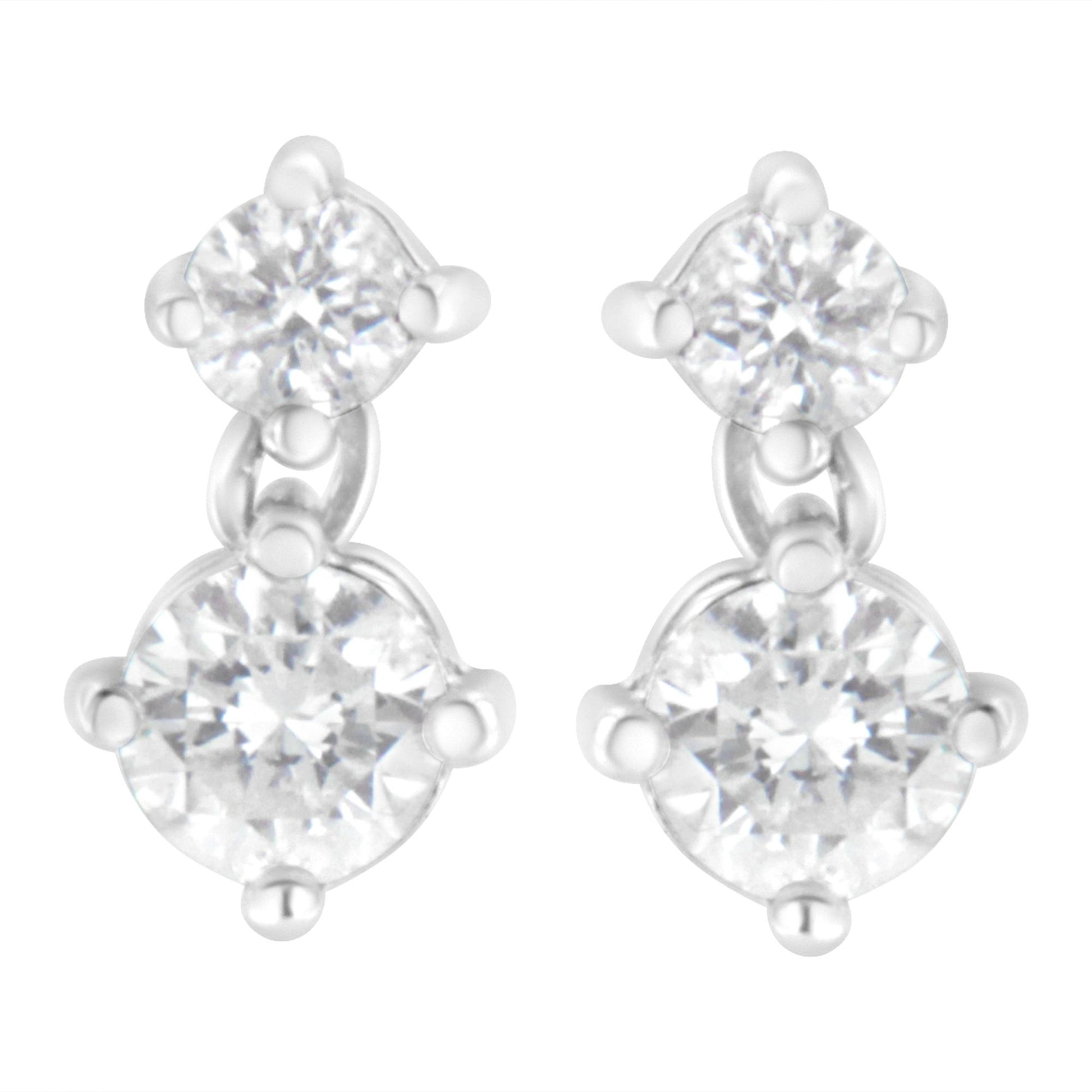 Front angle view of white metal earrings with two round white gemstones each in prong settings.