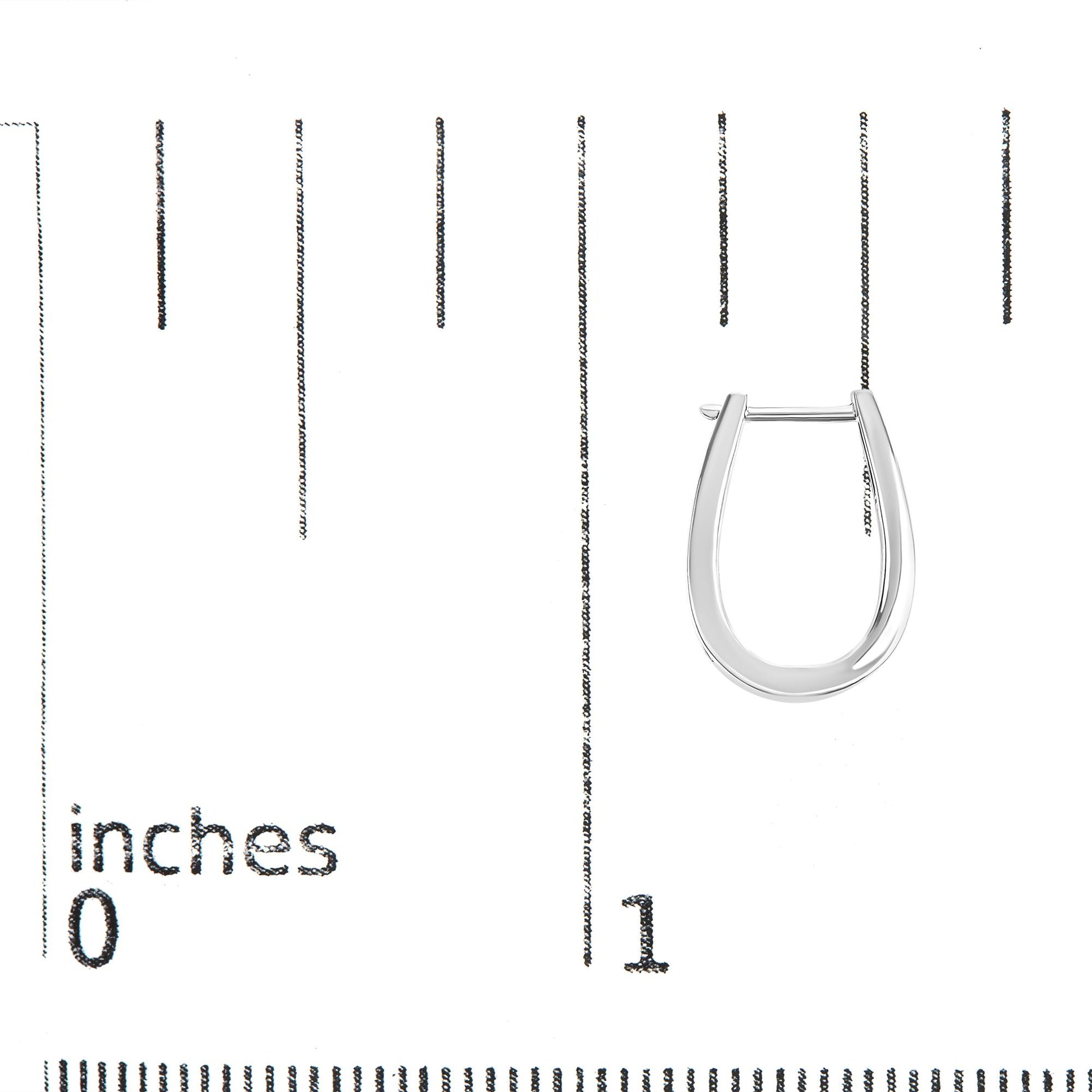 Close-up front view of a white metal earring with channel-set round white gemstones, placed on a ruler for size reference.