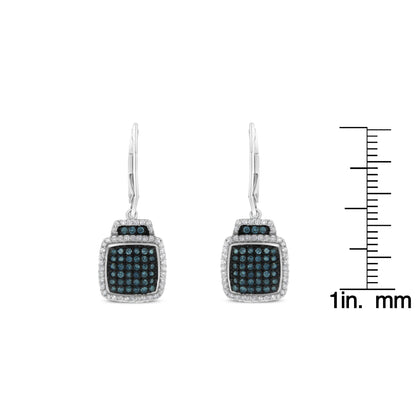 Front view of white metal earrings with square-shaped drops featuring blue pave-set round gemstones in the center, surrounded by prong-set white round gemstones, displayed next to a ruler for size reference.