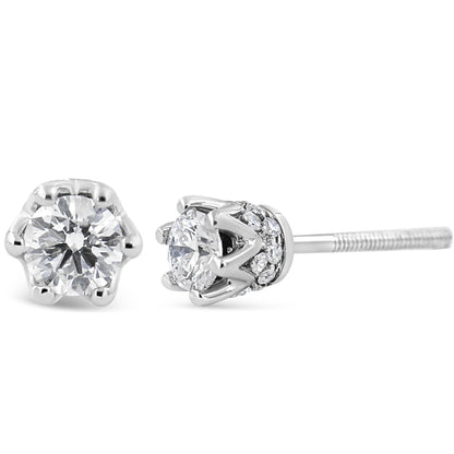 Close-up front and side view of a pair of white metal stud earrings with round white gemstones in prong settings and additional smaller round white gemstones in pave settings around the base.