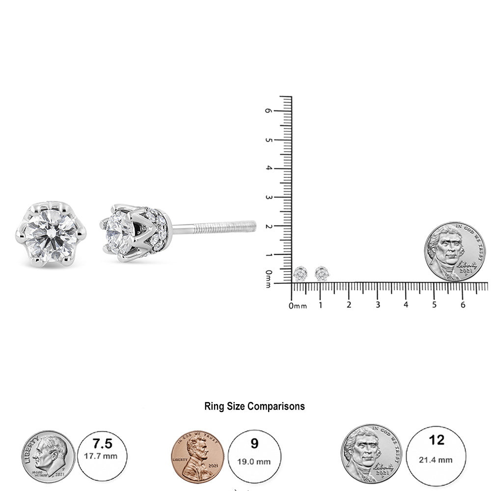 Close-up front and side angle of white metal stud earrings with one round prong-set white gemstone each, surrounded by multiple small round pave-set white gemstones, displayed next to a ruler and coin for size reference.