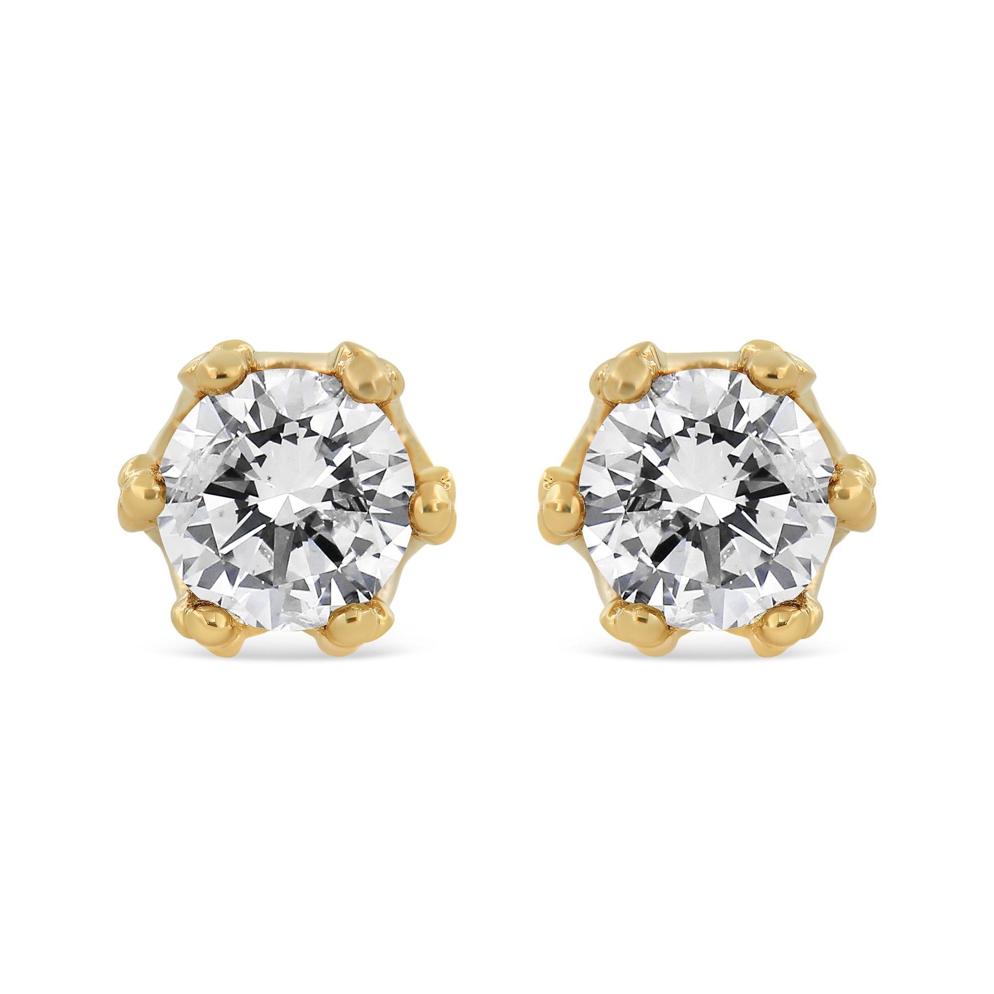 Front view of yellow metal stud earrings each featuring a large round white gemstone in prong setting.