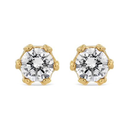 Front view of yellow metal stud earrings each featuring a large round white gemstone in prong setting.