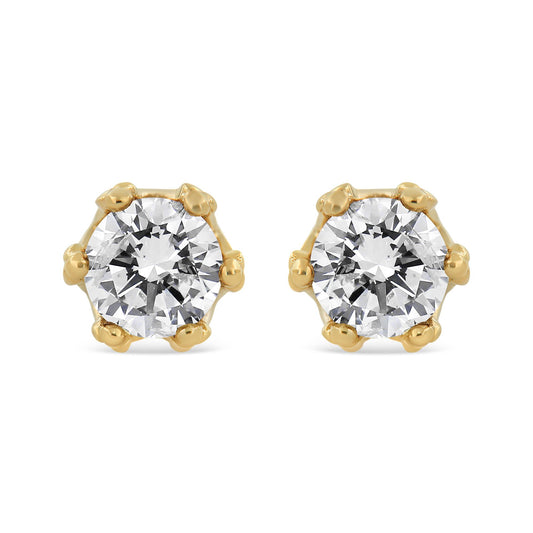 Front view of yellow metal stud earrings each featuring a large round white gemstone in prong setting.