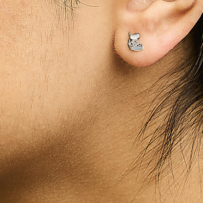 Close-up side view of a white metal earring with a round white gemstone in prong setting worn on a model's ear.