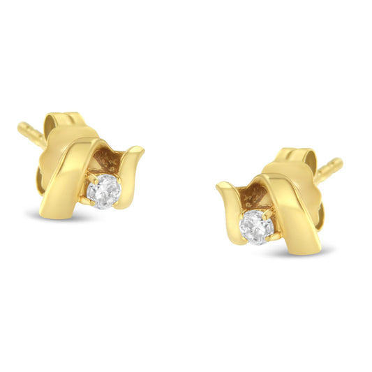 Pair of yellow metal stud earrings with a round white gemstone in prong setting, photographed at a slight angle.