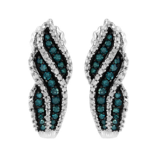 Pair of white metal earrings with wavy design, set with blue round gemstones in prong settings, shown from front angle.