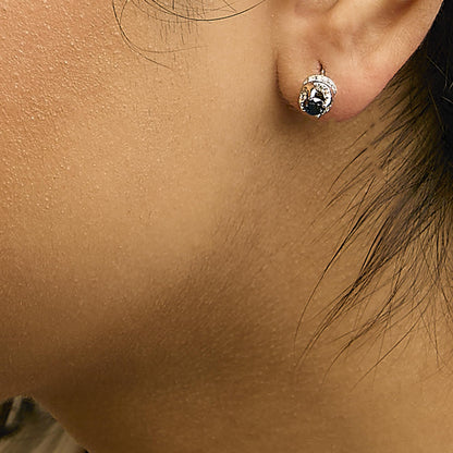 Close-up side view of a white metal earring worn on a model's ear, featuring round blue and white gemstones in prong settings.