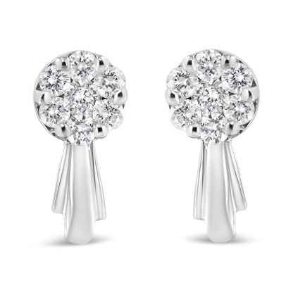 Front-facing shot of a pair of white metal earrings with clusters of round white gemstones in prong settings at the top and smooth elongated drops below.