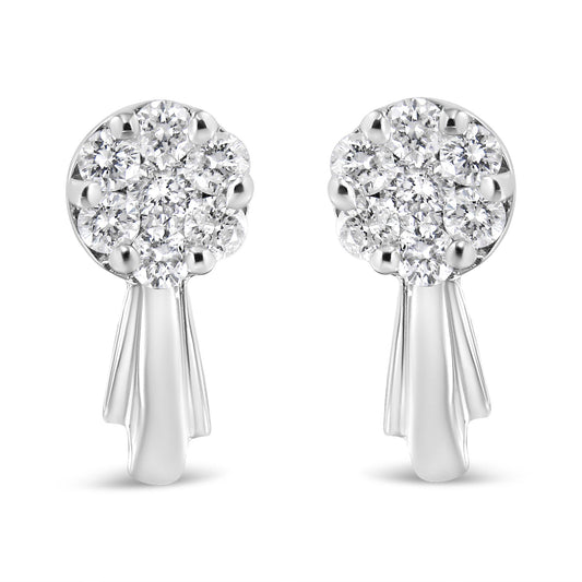 Front-facing shot of a pair of white metal earrings with clusters of round white gemstones in prong settings at the top and smooth elongated drops below.