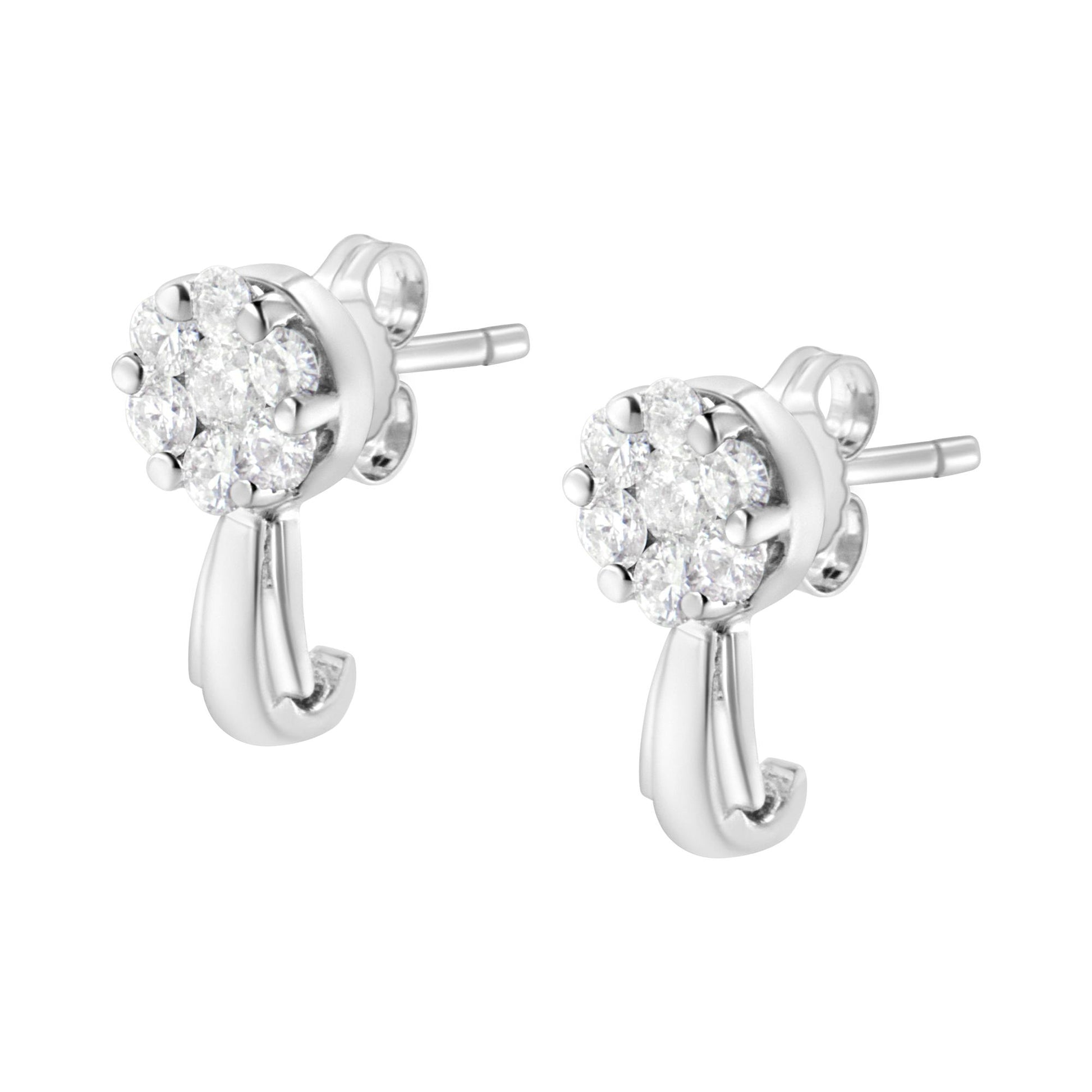 Close-up side angle of a pair of white metal stud earrings with cluster round white gemstones in prong settings and a curved metal detail hanging below.