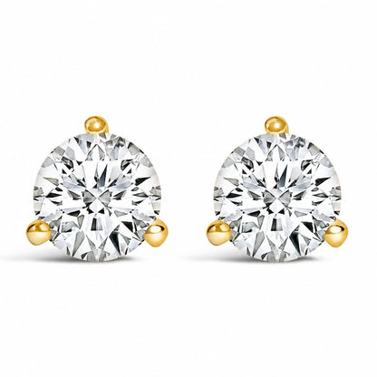 Close-up front view of a pair of yellow metal stud earrings, each featuring a round white gemstone in a three-prong setting.