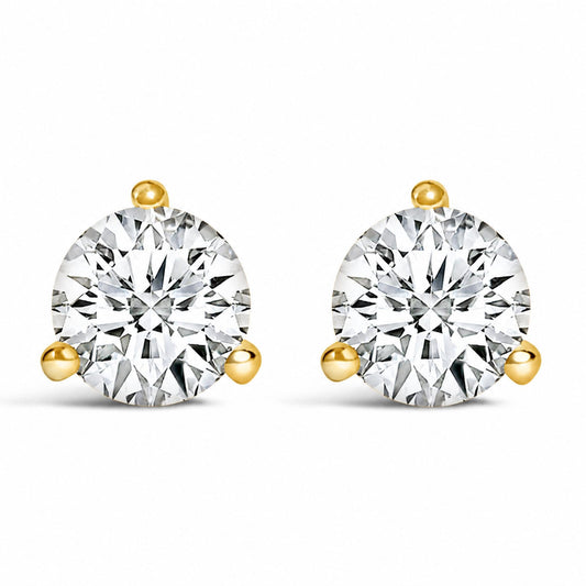 Close-up front view of a pair of yellow metal stud earrings, each featuring a round white gemstone in a three-prong setting.