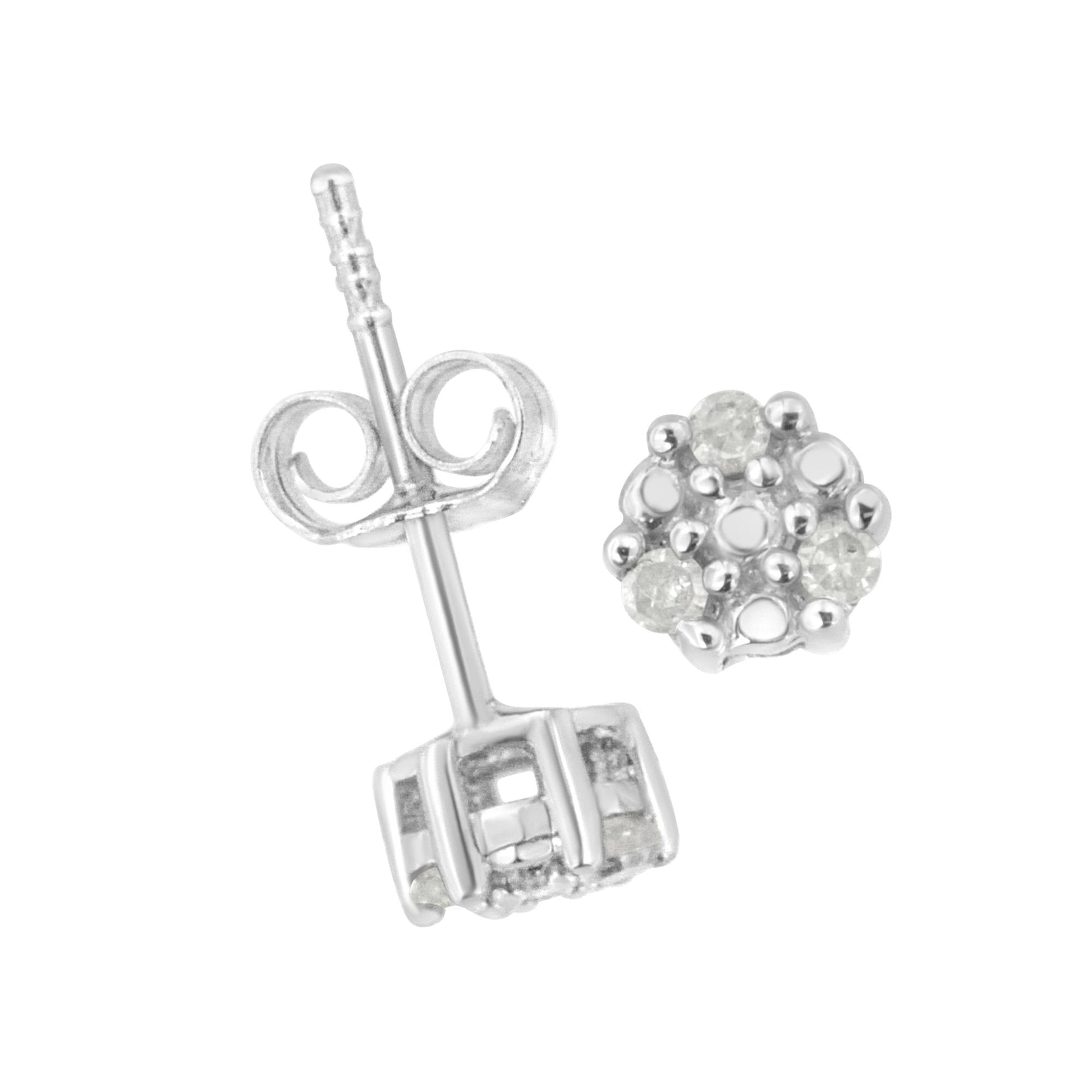 Close-up image of a pair of white metal stud earrings with round white gemstones in a prong setting, one showing the front cluster and the other showing the post and butterfly back, shot from an angled top-down perspective.