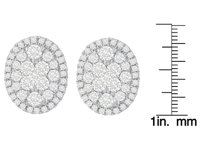 Pair of yellow metal oval earrings set with multiple round white gemstones in prong settings, shown from front on with a ruler for size reference.
