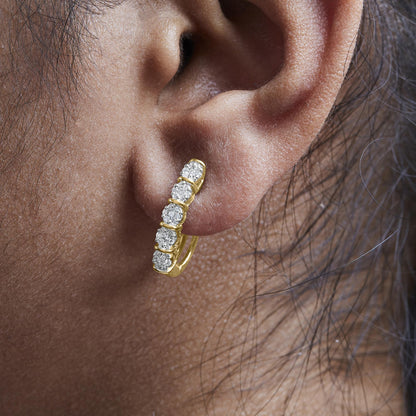 Close-up side angle of a yellow metal earring with a vertical row of round white gemstones in prong settings, shown worn on a model.