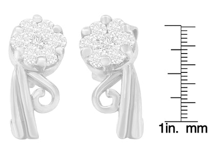 Pair of white metal earrings with cluster of round white gemstones in prong setting, shown at front angle with scale ruler for size reference.