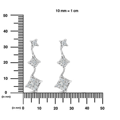 Pair of white metal earrings with three connected square clusters of white gemstones in a descending arrangement, displayed front-facing on a ruler for size reference.