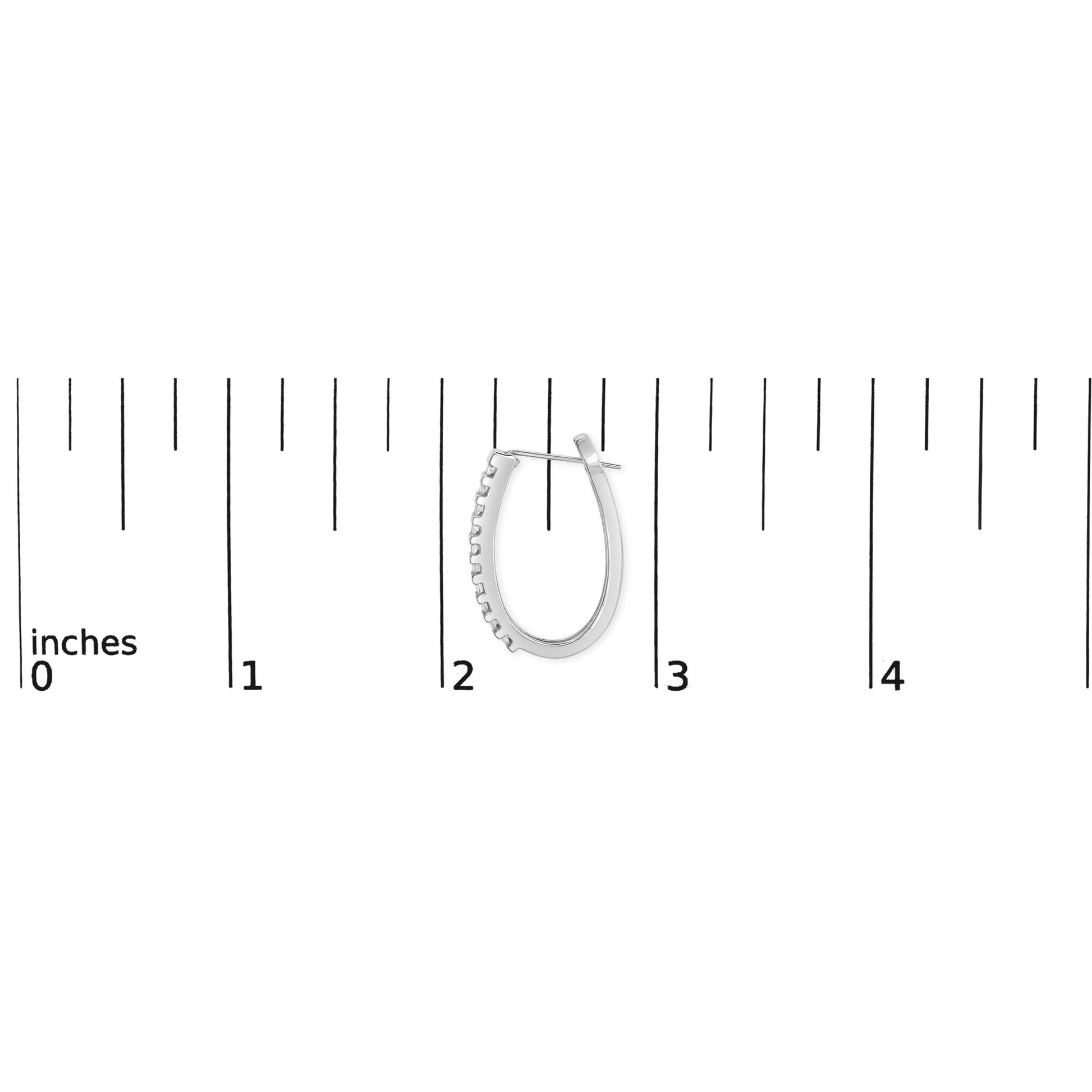 Close-up of one white metal earring with channel-set white baguette-shaped gemstones placed next to a ruler for size reference.